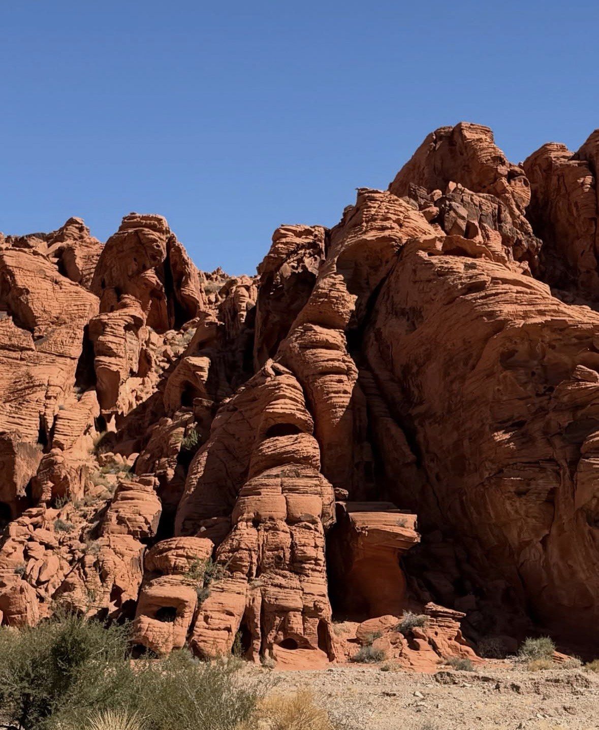 Layered red sandstone cliffs and hoodoos beneath clear blue sky