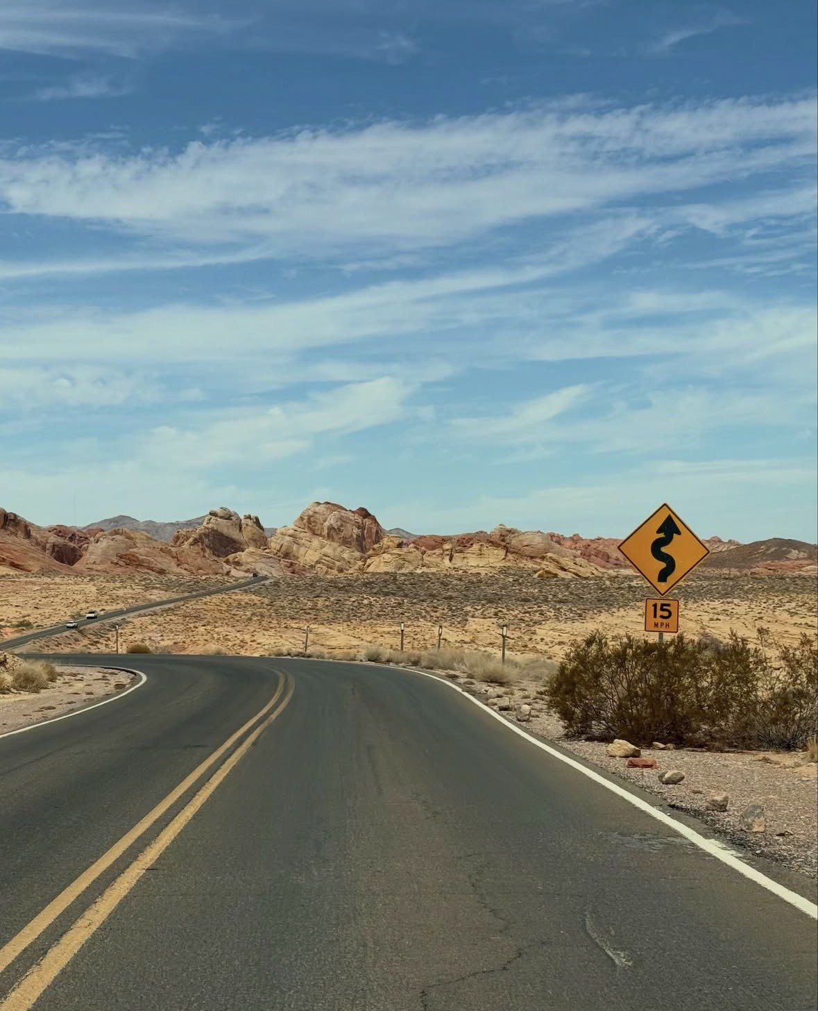 Winding road sign with 15 mph plate on desert highway